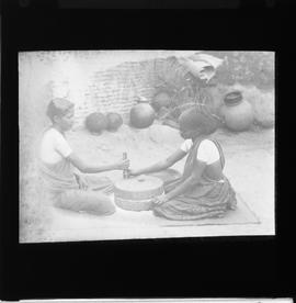 Two women operating hand quern