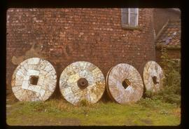 Four millstones lying against wall of tower mill