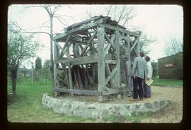 Two men inspecting preserved buck framing of "cavier" windmill on ground
