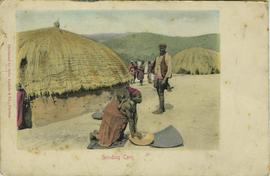 Woman with baby grinding corn