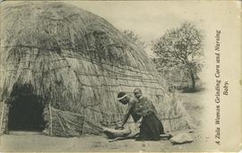 A Zulu woman grinding corn and nursing a baby
