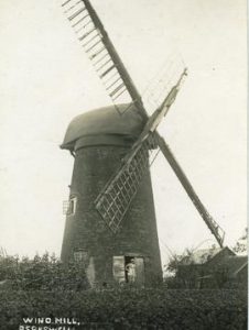 Postcard of derelict mill with cap and part of sails