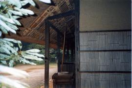 Photograph of a hut with a quernstone
