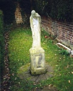 Photograph of a millstone with statue on top, Cedar Court, Coombe, Greater London