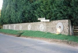 Photograph of seven millstones set in a stone wall, Slaughter Farm, Bourton on the Water, Gloucester