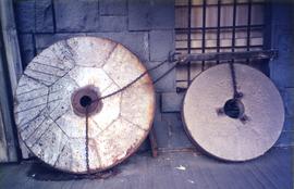 Photograph of two French millstones against a wall