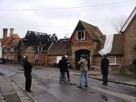 Exterior view of damage, with film crew and fireman