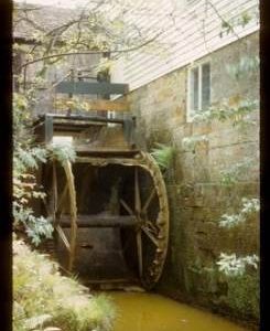 Exterior of part of watermill building showing derelict wheel