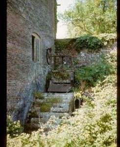 Part of exterior of derelict watermill showing wheel