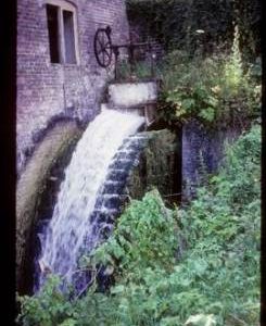 Part of exterior of derelict watermill showing wheel