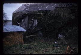 Exterior view of stone watermill building with wheel