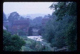 Exterior view of double brick watermill building with wheels