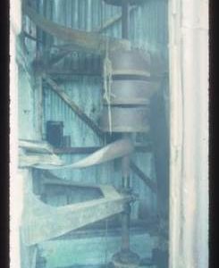 Vertical shaft with pulleys in corrugated iron enclosure - associated with turbine